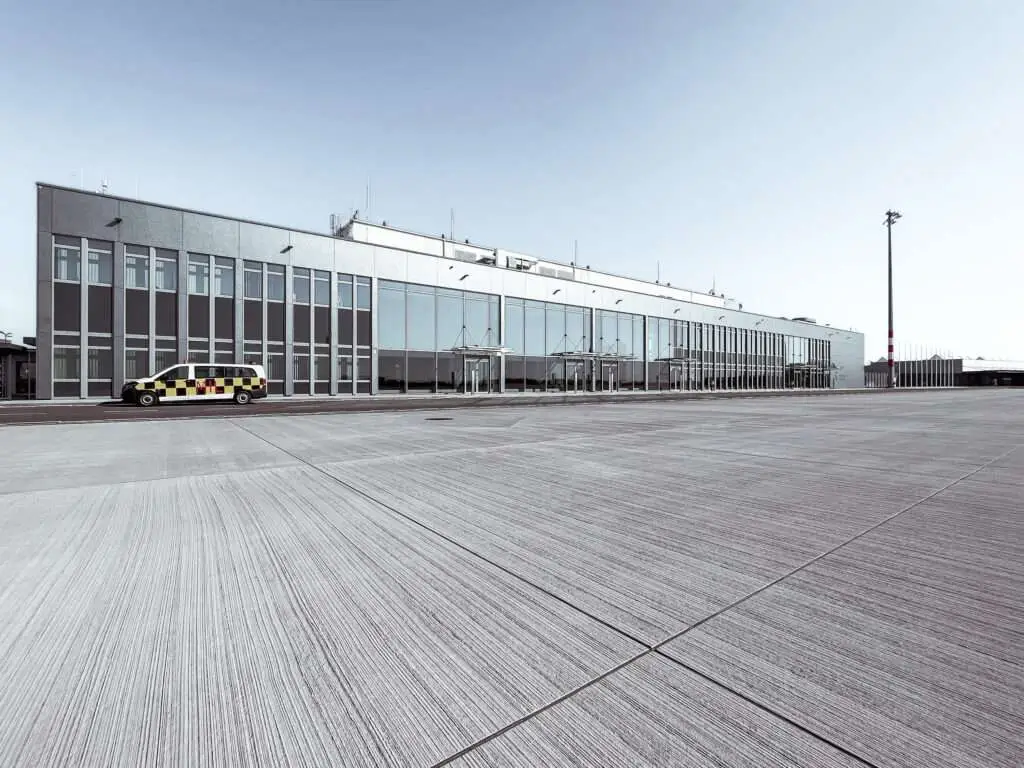 Flughafenterminal mit viel Glas und viel Auto davor