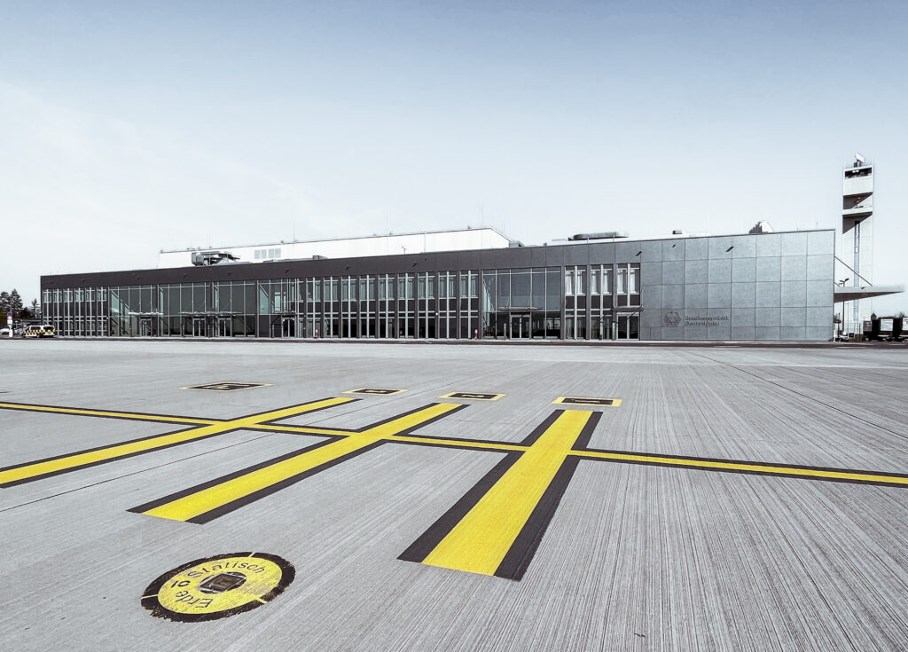 gelbe Linien im Vordergrund mit Flughafen im Hintergrund