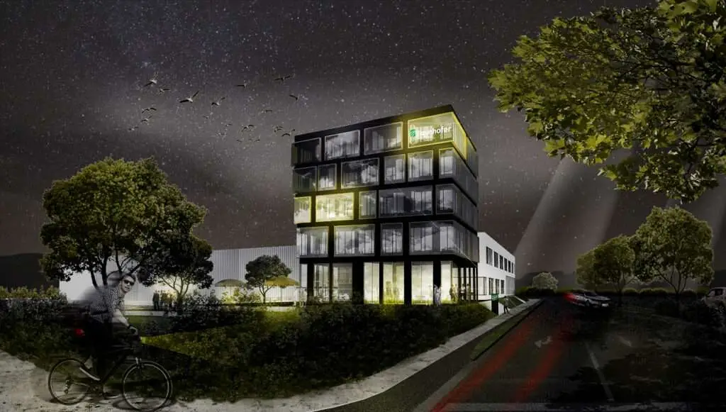 Gebäude bei Nacht mit Straße und Radfahrer im Vordergrund