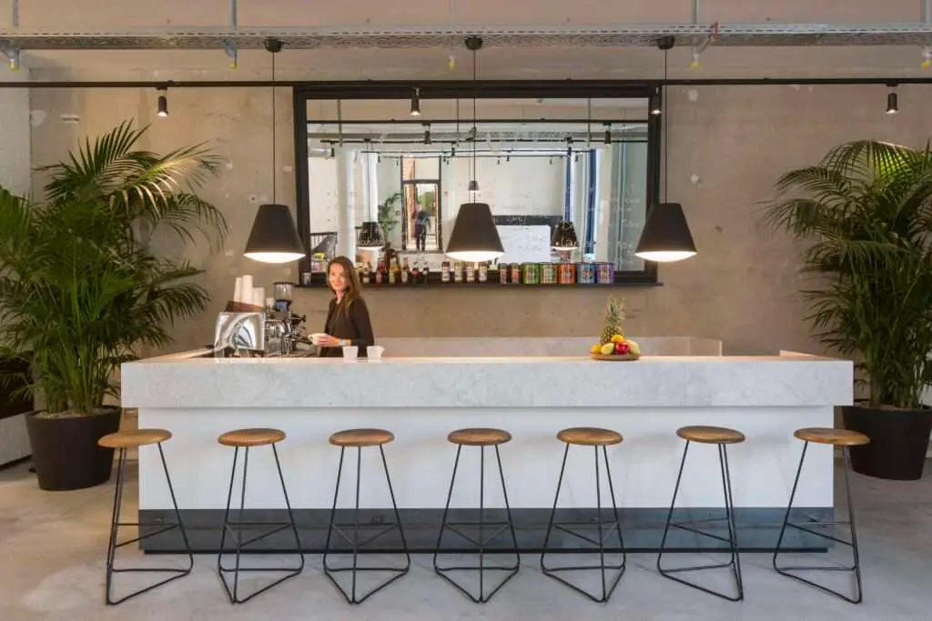 Barbereich mit Barhockern, viel Beton und einer Frau