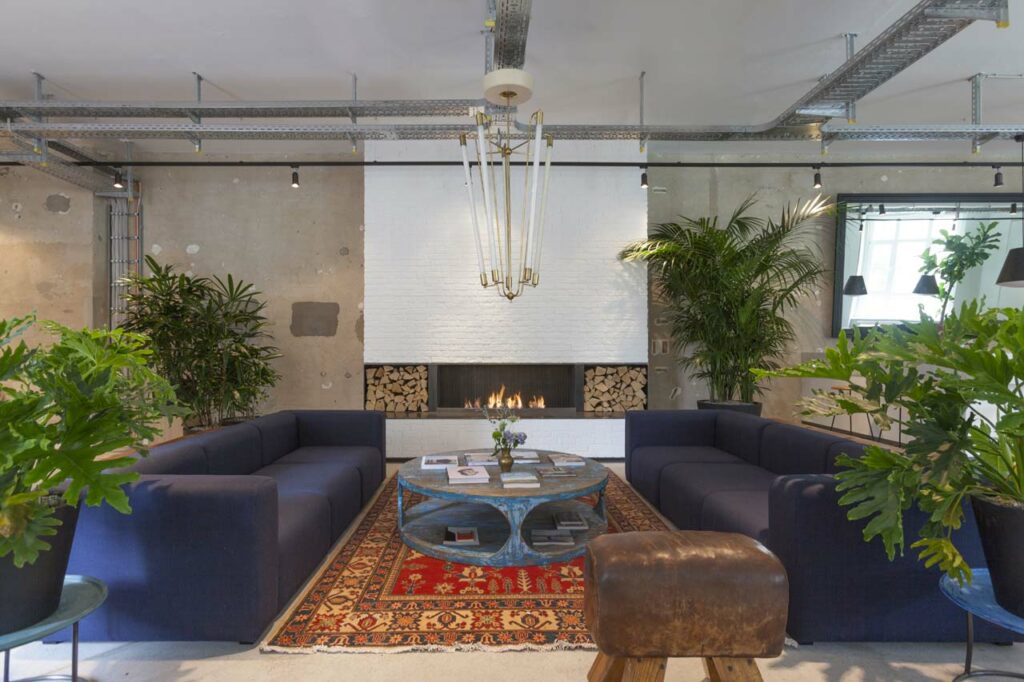 Loungebereich mit Kamin, rundem Couchtisch und blauen Sofas