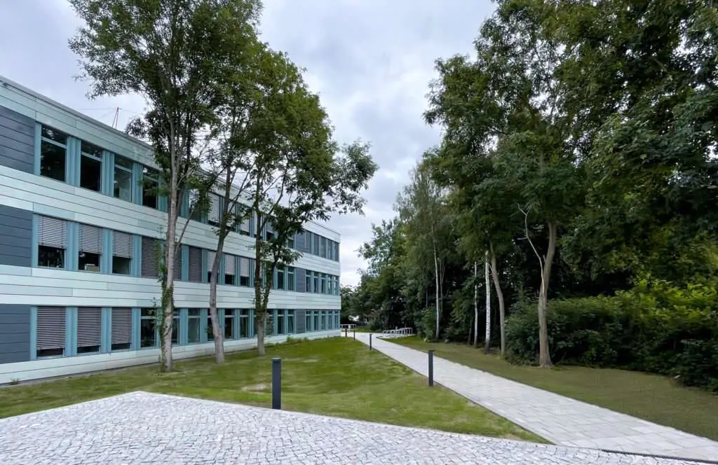 Parkanlage mit Steinwegen Bäumen und einem Gebäude auf der linken Seite