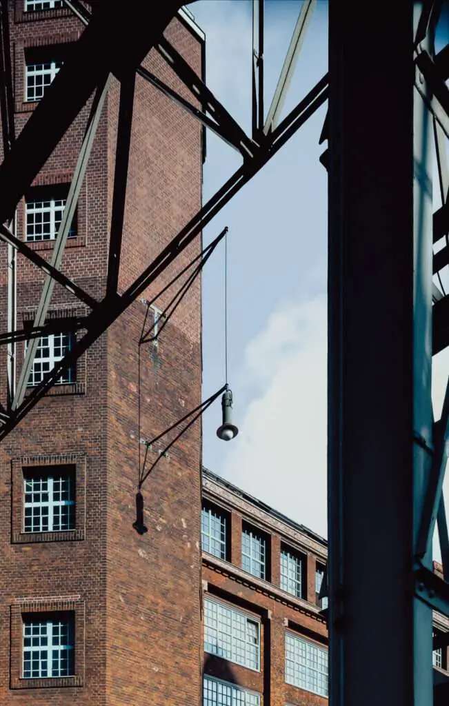 Altes Industriegebäude mit viel Fenstern und Backsteinfassade. Metallkonstruktion im Vordergrund