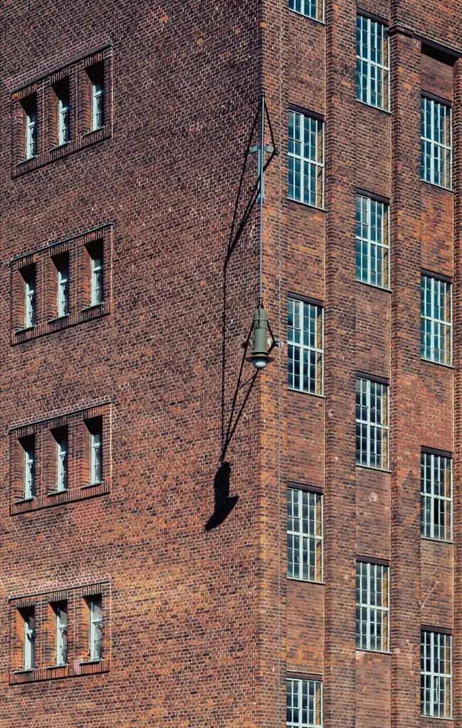 Außenwand eines alten Backsteingebäudes mit Fenstern und Lampen