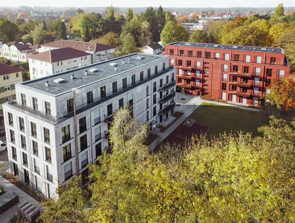 Drohnenaufnahme von zwei Wohnblöcken mit Baum im Vordergrund