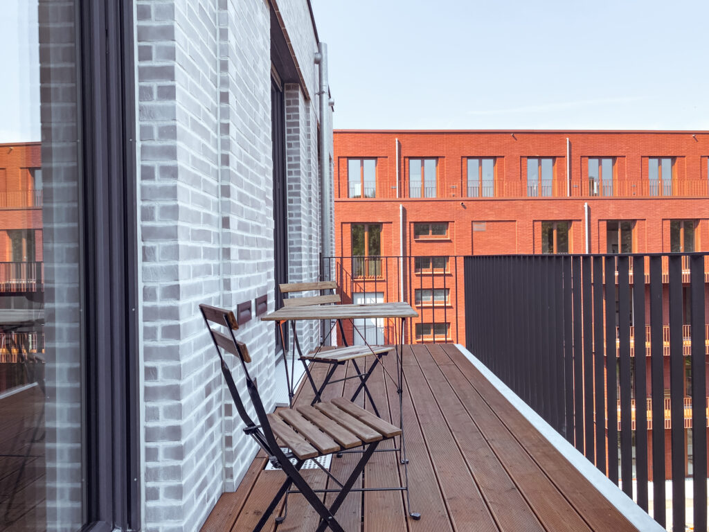 Balkon eines Modernen Wohnhauses mit Gartenmöbeln und Holzboden