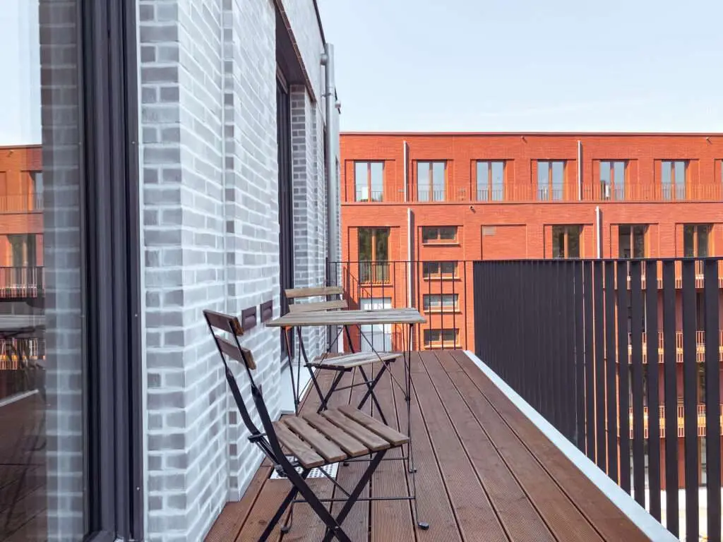 Balkon eines Modernen Wohnhauses mit Gartenmöbeln und Holzboden