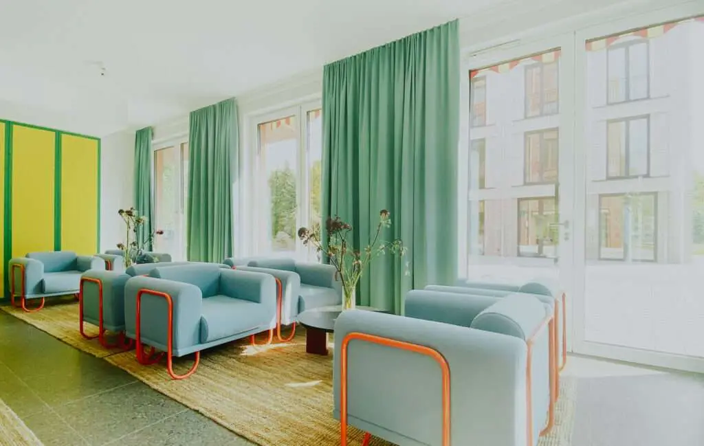 in retro Stil eingerichteter Aufenthaltsraum mit blauen Sitzmöbeln und grünen Vorhängen