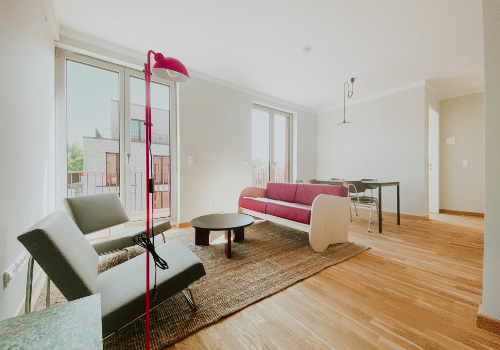 Wohnzimmer mit Teppich, Sitzgelegenheiten und roten Farbakzenten