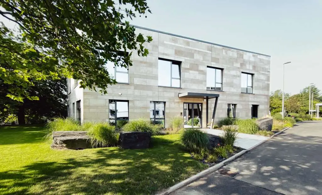 modernes Bürogebäude mit einem Baum und Rasen im Vordergrund