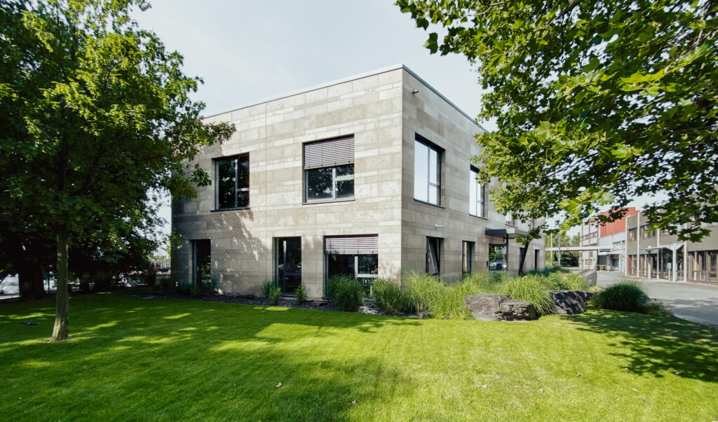 Kombination aus einer großen Rasenfläche und einer gradlinigen Architektur im Hintergrund