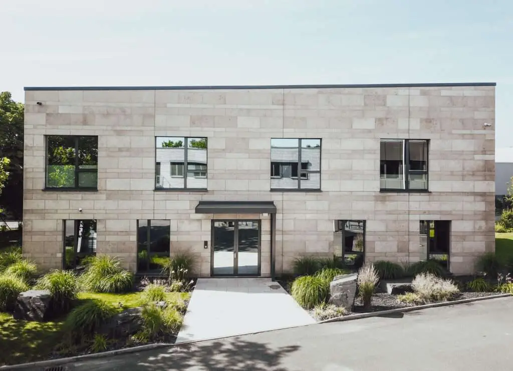 Außenansicht von einem Haut mit Steinfassade und Grünfläche im Vordergrund