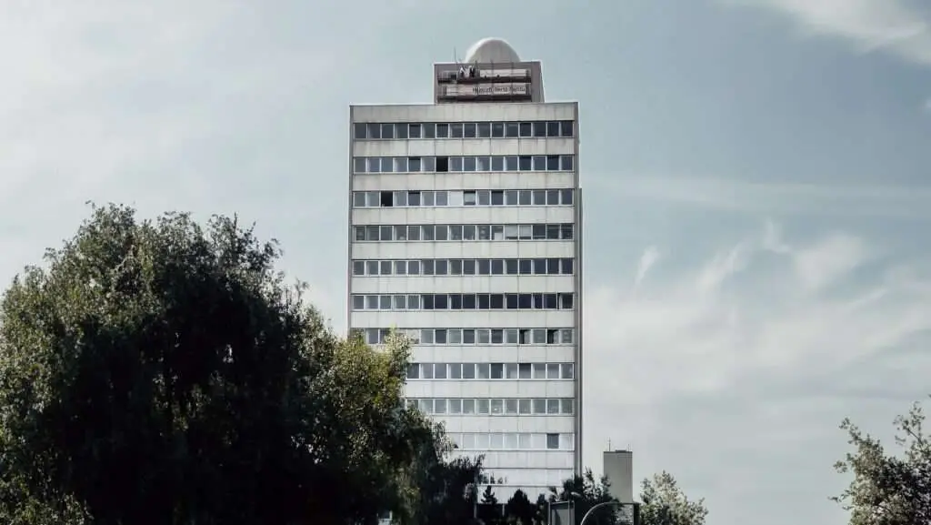 in die Jahre gekommenes Hochhaus mit Technik auf dem Dach