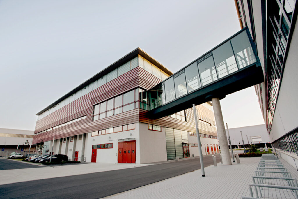 Bürogebäude mit roten Zierelementen und einem Glasübergang zu anderem Gebäude
