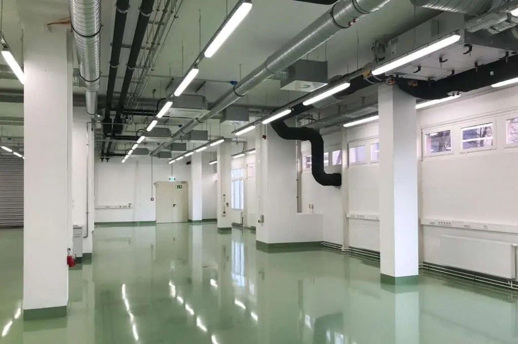 leerer hoher Raum mit vielen Rohren und einem reflektierendem Boden