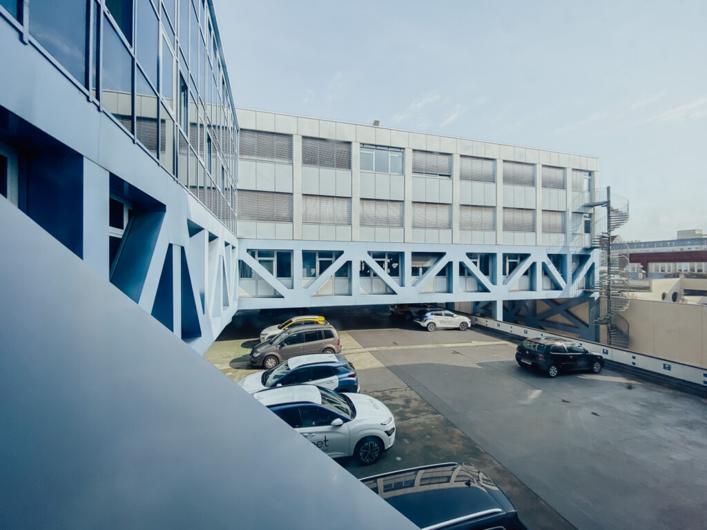 Streben im Vordergrund mit Blick auf den Parkplatz eines Industriegebäudes