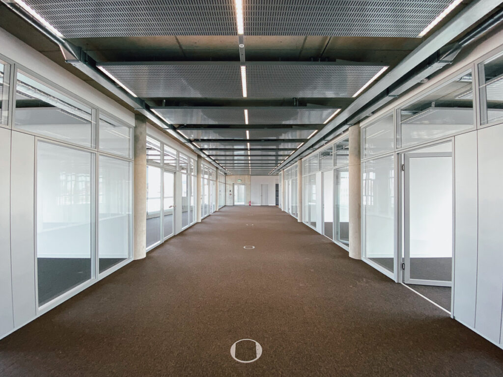 Büroflächenkorridor mit viel Glas an den Seiten und einer Betondecke